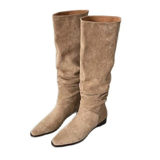 Bottes hautes et mollets larges en daim beiges sur fond blanc.