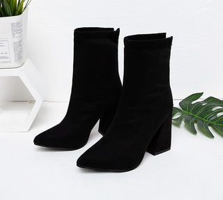 Bottes noires à talons avec zip à l'arrière et bouts pointus. Feuille de plante en arrière plan.