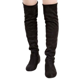 Bottes noires en cuir, portées par une femme, jambes de femme, sur fond blanc