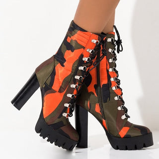 Paire de bottes à talons au camouflage orange et vert sur fond blanc.
