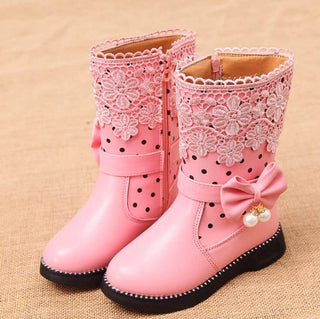 On voit une paire de bottes de pluie très féminines, roses avec des perles, de la dentelle et des noeuds. Bottes de princesse pour petites filles.