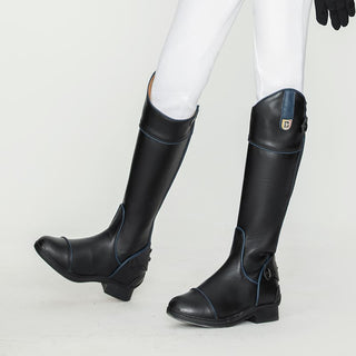 Bottes d'équitation noir avec des rainures bleus portée par un enfant avec un pantalon blanc et des gants noirs