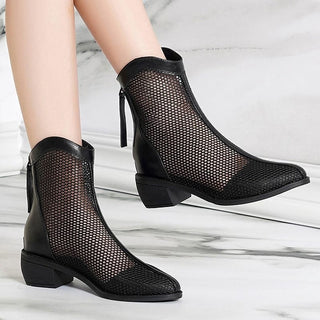 Photo d'une paire de botte d'été noires en mesh portées avec un fond en marbre.