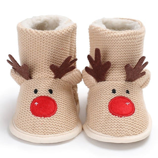 Très jolies bottes en mailles tricotées esprit de Noël, beiges, avec un motif renne de Noël : deux petites cornes dépassent sur le dessus de la botte fourrée et des yeux et un nez rouge sont cousus en-dessous.