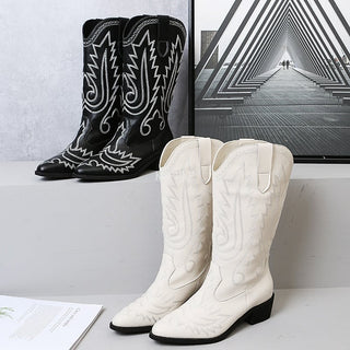 Photo de deux paires de bottes de cowboy brodées, une noire et une blanche sur un présentoir.