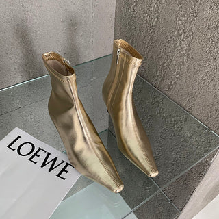 Photo d'une paire de bottines dorées sur une plaque de verre avec un magazine à coté