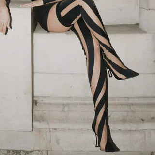 Jambes de femme assise, bottes chaussettes rayées à talons, fauteuil blanc