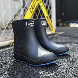 bottines noirs avec plateforme de pluie, à enfiler, sont présentées sur du bitume devant un grillage, elle sont noires avec le dessous de la semelle bleu