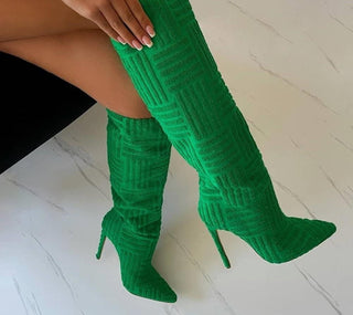 des bottes vertes hautes avec une main dessus sur un sol blanc