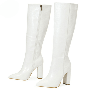 Paire de bottes hautes blanches, de trois-quarts vers la gauche. On voit la face interne avec la fermeture éclair de la botte en arrière-plan, et on voit la face externe de la botte en premier plan. Le tout sur fond blanc.