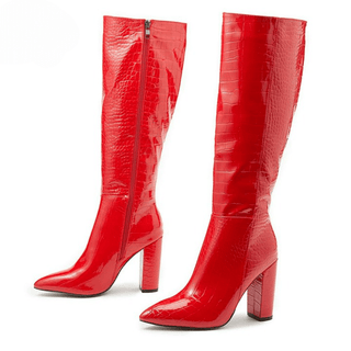 Paire de bottes hautes rouges, de trois-quarts vers la gauche. On voit la face interne avec la fermeture éclair de la botte en arrière-plan, et on voit la face externe de la botte en premier plan. Le tout sur fond blanc.