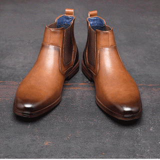 Paire de bottines homme classique couleur camel de face, avec le bout plus foncé presque noir. Sur un sol gris.
